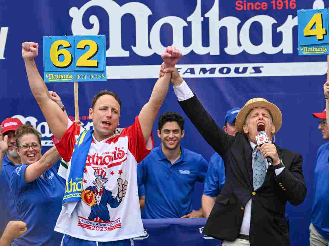 Chestnut raises his arms in victory, holding hands with the emcee, onstage in Coney Island.