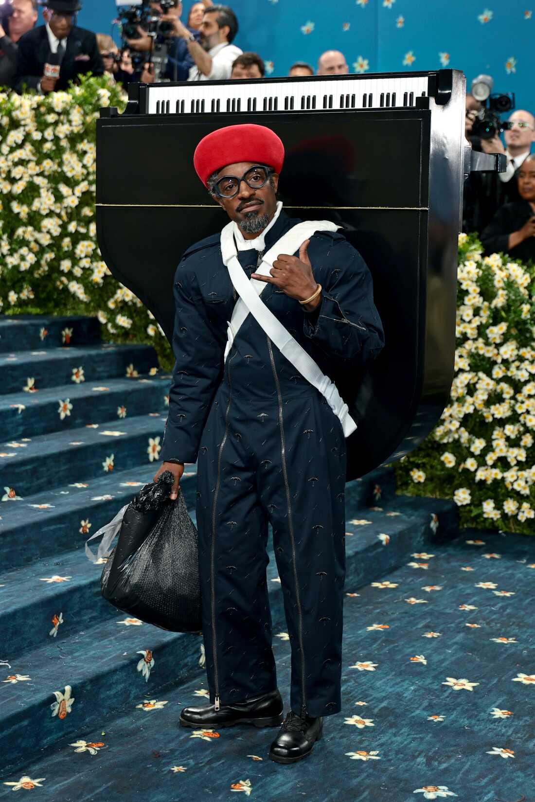 André 3000, wearing a piano strapped to his back, attends the 2025 Met Gala.